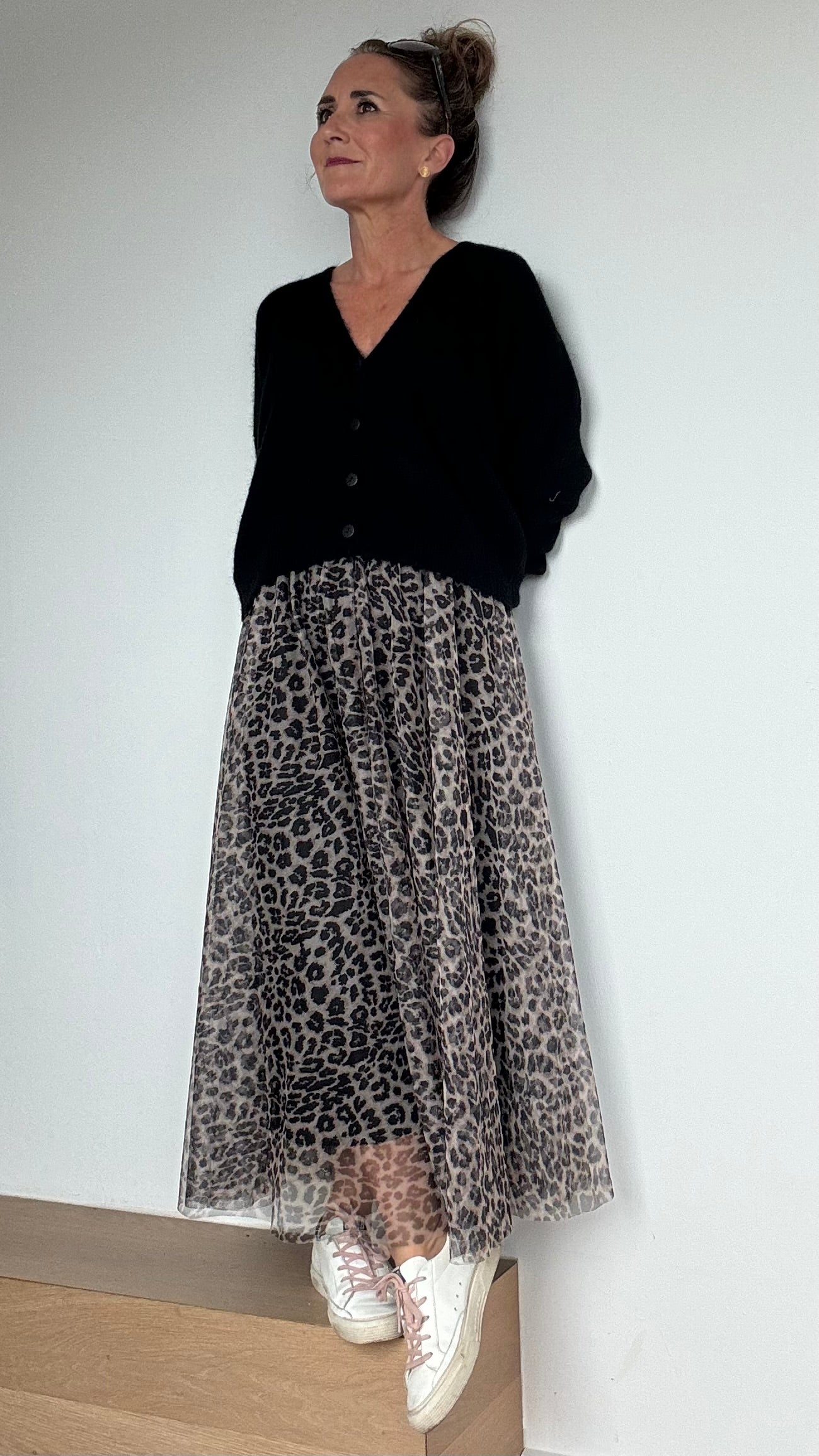 Frau trägt einen schwarzen Cardigan, dazu den Tüllrock in der Farbvariante heller Leo-Print. Details findest du in unserer Produktbeschreibung.