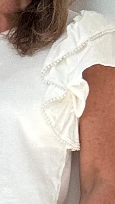 Top in cremeweiß mit Flügelärmelchen und einem Rand mit aufgestickten Perlen. Details findest du in der Produktbeschreibung.