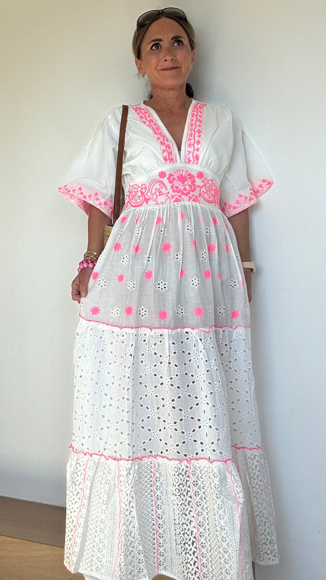 Sommerliches Maxikleid Boho Breeze Dress – White Edition aus weißer Baumwolle mit pinkfarbener Stickerei. Luftiger Stufenschnitt mit kurzen Ärmeln, V-Ausschnitt und elastischem Rückenbund. Länge ca. 133 cm, passt locker von Größe 36–40. Nicht unterfüttert – ideal für heiße Tage oder mit Unterkleid tragbar.