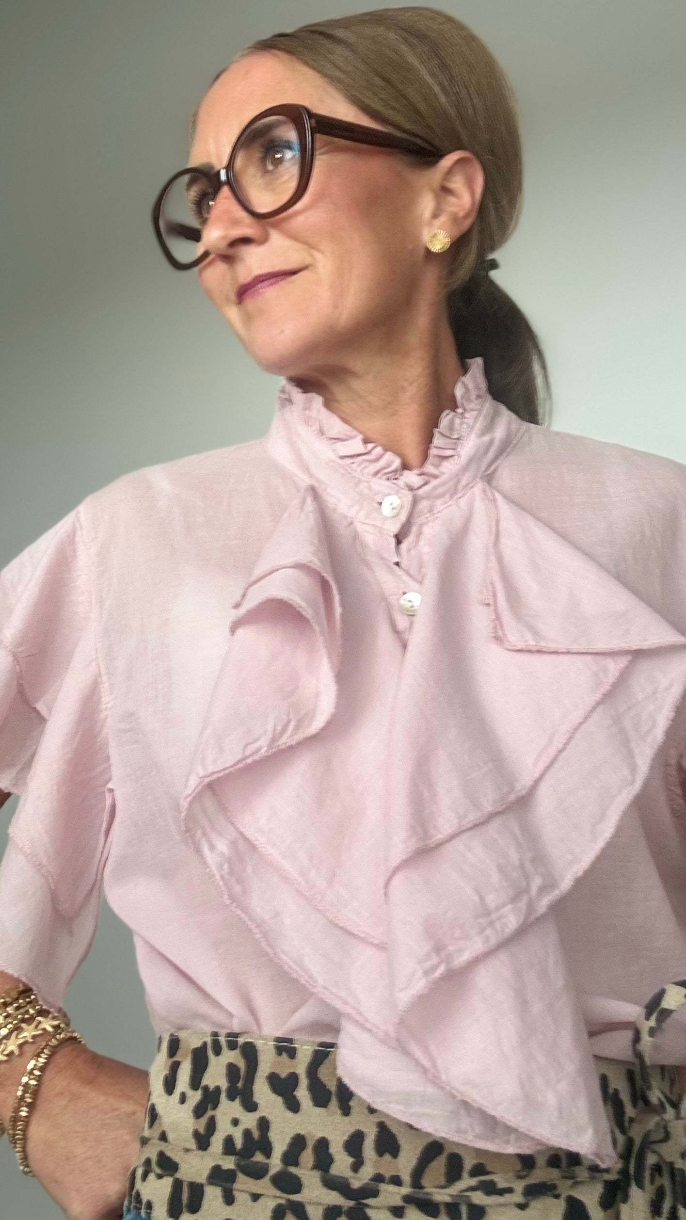 Ärmellose Bluse aus 100 % Baumwolle in zartem Altrosa mit feinen Details: Wasserfallartige Volants zieren die Knopfleiste sowie die leichten Volant-Ärmel. Die Bluse hat einen kleinen Stehkragen mit Rüschen, ist gerade geschnitten und etwa 62 cm lang. Locker und stilvoll kombiniert mit Jeans und Taillengürtel oder elegant mit Rock oder Blazer tragbar – ideal für feminine Looks mit Statement-Charakter.