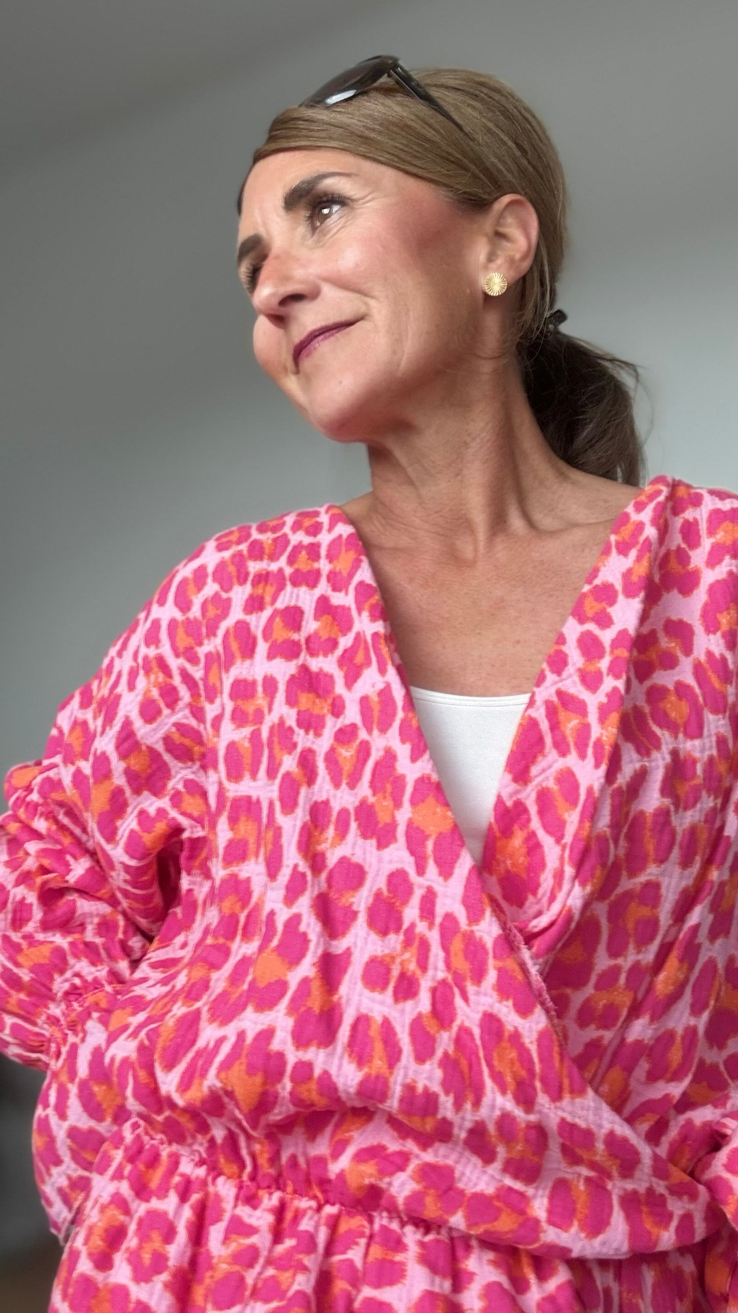 Sommerliche Wickelbluse aus pinkfarbenem Musselin mit Leoprint, Puffärmeln in Fledermausform und kurzem Rüschenschößchen. Seitlich mit Schleife bindbar, innenliegendes elastisches Bündchen für sicheren Sitz. Länge 55 cm, Achsel zu Achsel 60 cm. Locker geschnitten für Größen 34–42, ideal kombinierbar mit Jeans, Rock oder als Überwurf über ein Kleid.