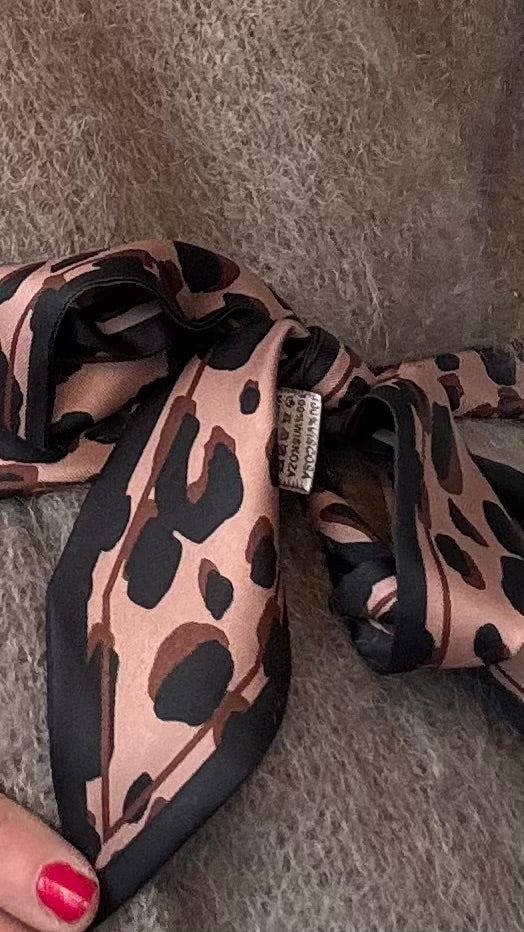Leo-Band aus 100% Viskose, Länge 157 cm, Breite 5 cm, in hellem und dunklem Leo-Print. Spitz zulaufende Enden für vielseitige Stylingmöglichkeiten: als Halsband, Gürtel, Haarband oder Accessoire für Taschen.
