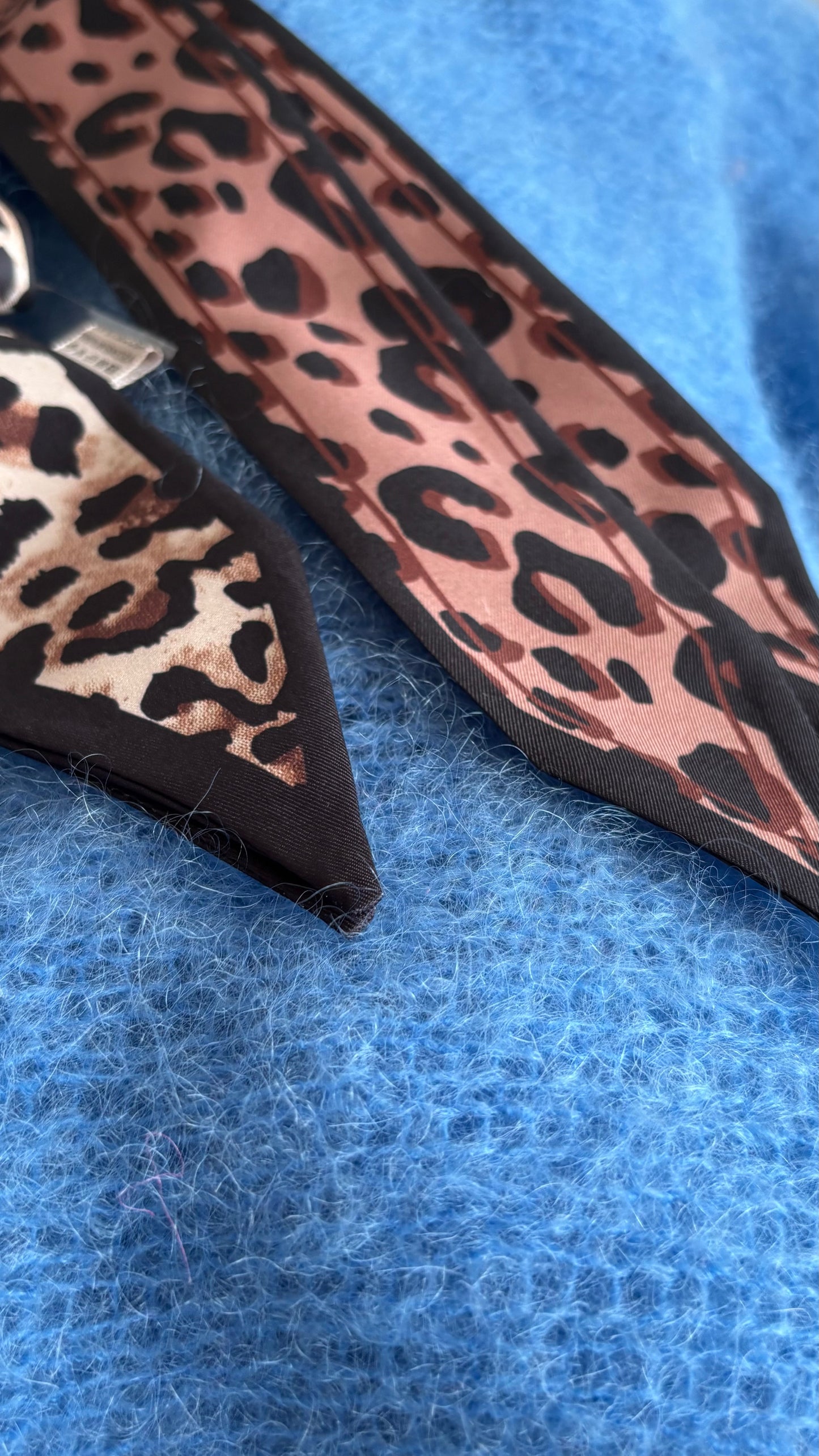 Leo-Band aus 100% Viskose, Länge 157 cm, Breite 5 cm, in hellem und dunklem Leo-Print. Spitz zulaufende Enden für vielseitige Stylingmöglichkeiten: als Halsband, Gürtel, Haarband oder Accessoire für Taschen.