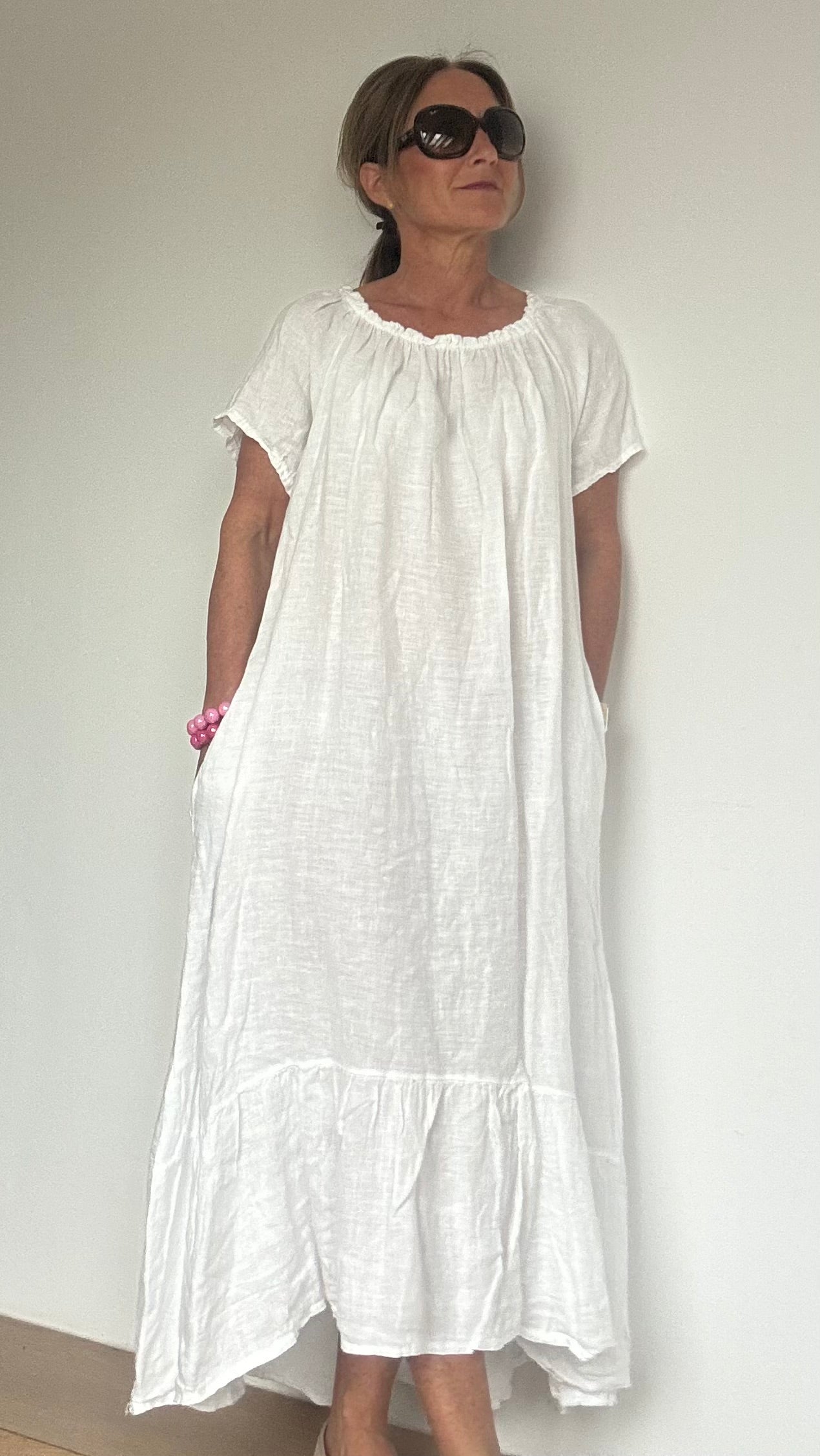 Kurzärmliges Leinenkleid mit elastischem Halsausschnitt und Volant-Abschluss, gerade und luftig geschnitten. Länge vorne 110 cm, hinten leicht verlängert. Mit Eingriffstaschen und vielseitig tragbar – klassisch oder als Carmenkleid. Figurumspielend und ideal für Petite-Frauen. Aus 100 % Leinen für sommerlichen Komfort.