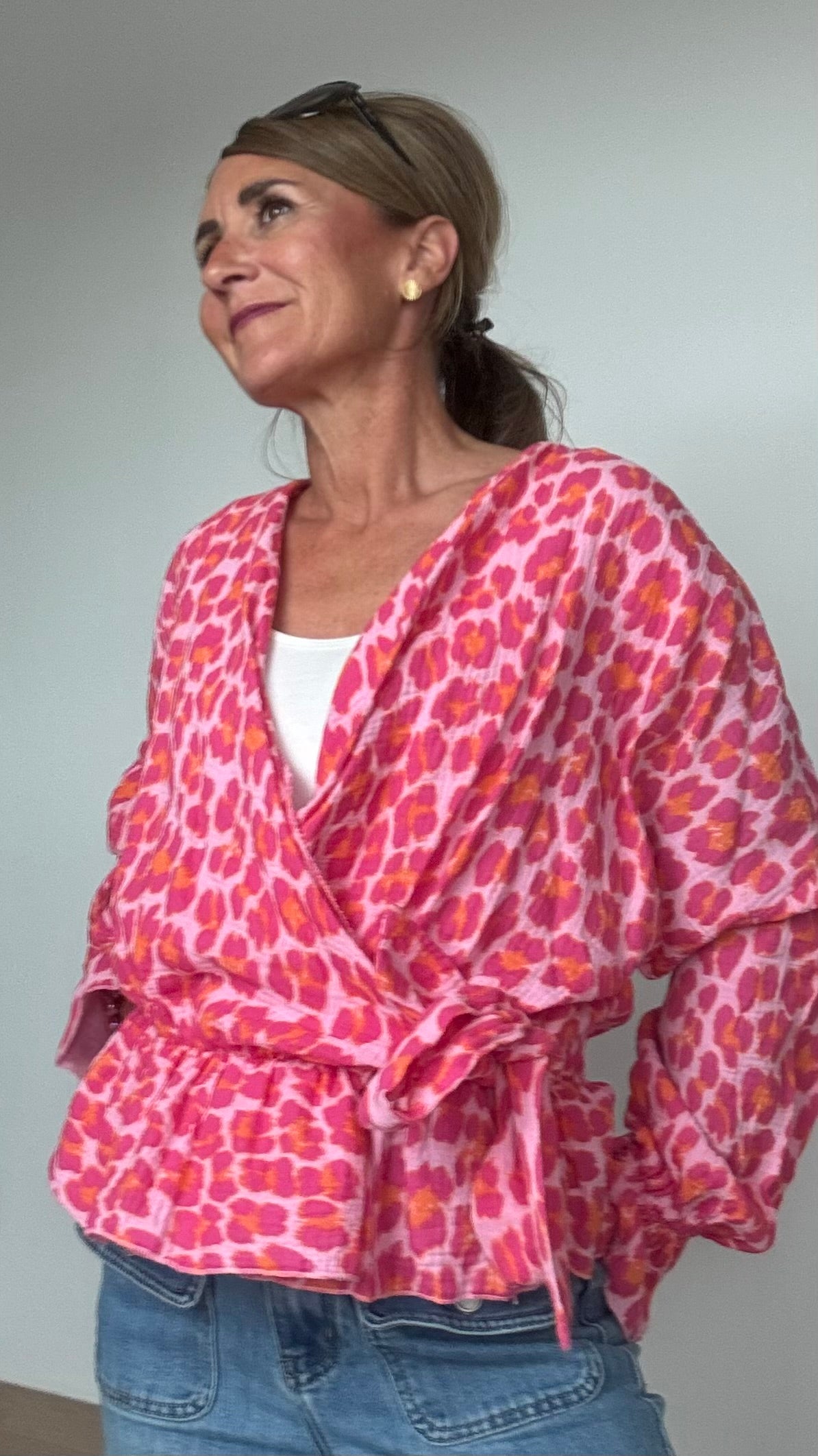 ommerliche Wickelbluse aus pinkfarbenem Musselin mit Leoprint, Puffärmeln in Fledermausform und kurzem Rüschenschößchen. Seitlich mit Schleife bindbar, innenliegendes elastisches Bündchen für sicheren Sitz. Länge 55 cm, Achsel zu Achsel 60 cm. Locker geschnitten für Größen 34–42, ideal kombinierbar mit Jeans, Rock oder als Überwurf über ein Kleid.