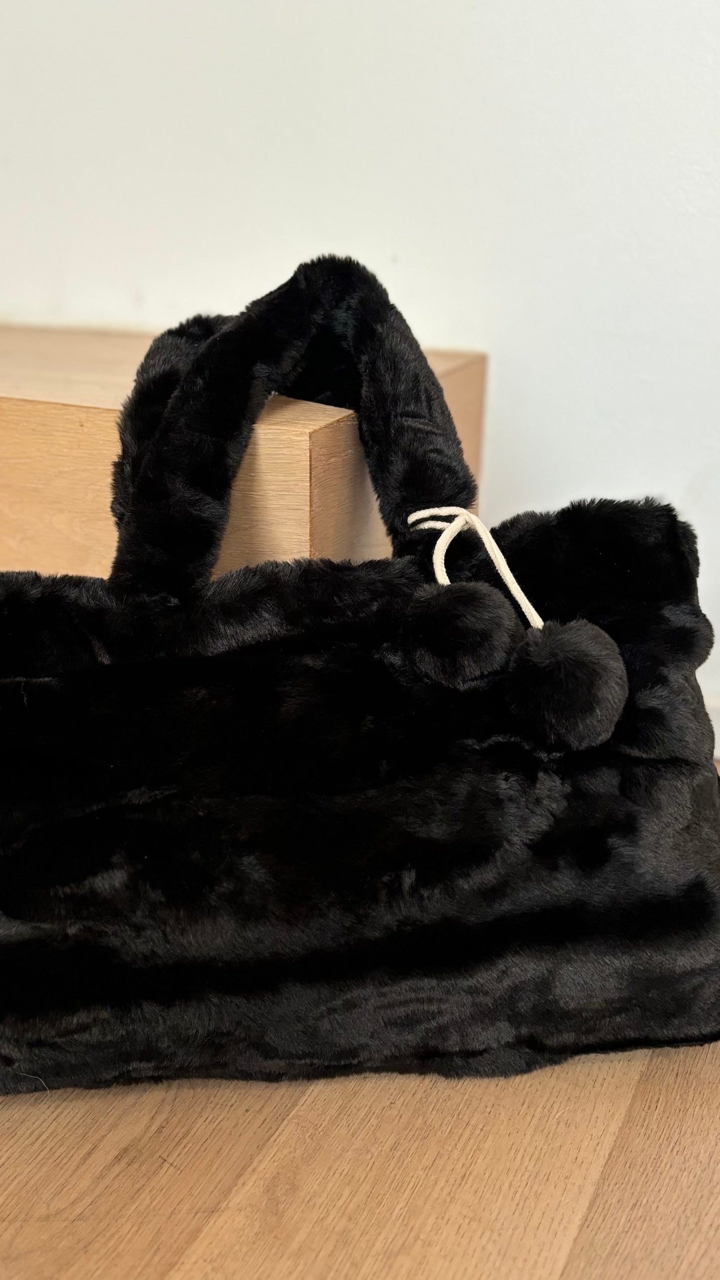 Cosy Couture Faux Fur Shopper in Schwarz mit den Maßen 29 x 45 x 11 cm. Die Tasche ist mit einem Reißverschluss schließbar und hat einen abnehmbaren Extra-Tragegurt für vielseitige Tragemöglichkeiten. Ausgestattet mit zwei abnehmbaren Zierbommel für einen individuellen Look."