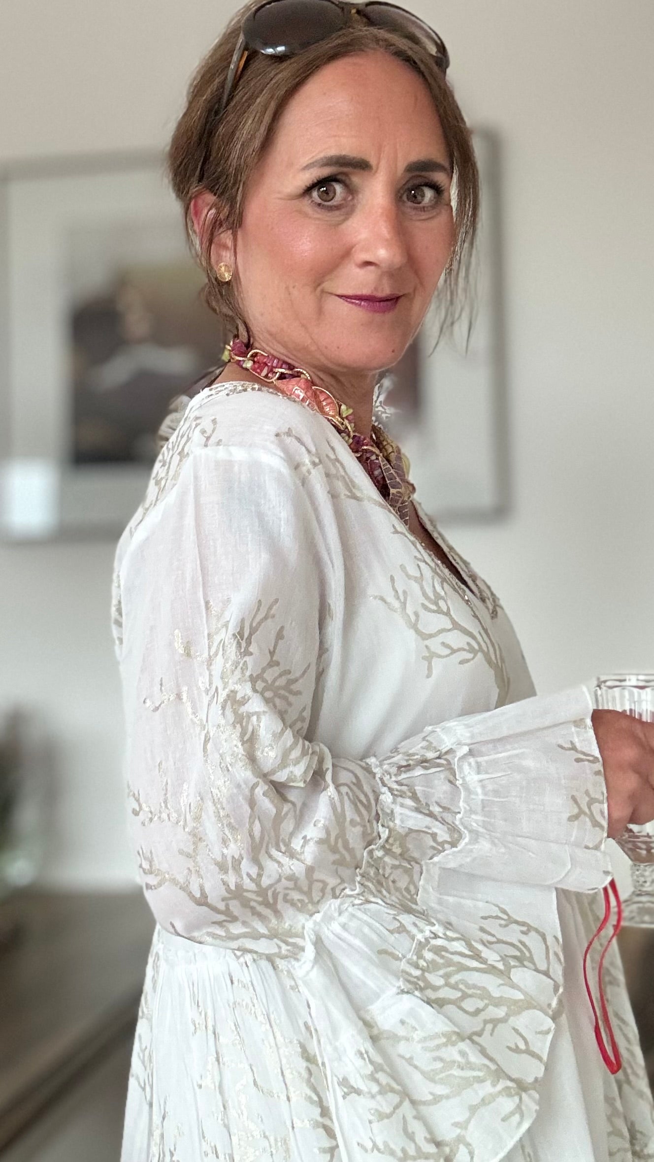 Kurzes Tunikakleid in zartem Weiß von Isla Bonita by SIGRIS. Eleganter V-Ausschnitt mit zartem goldenen Korallenmuster und Verzierungen aus gold- und silbernen Stäbchenperlen. Gesamtlänge 84 cm, Brustumfang 56 cm in der halben Weite. Luftig und ideal für sonnige Tage. Zusammensetzung: 100% Baumwolle