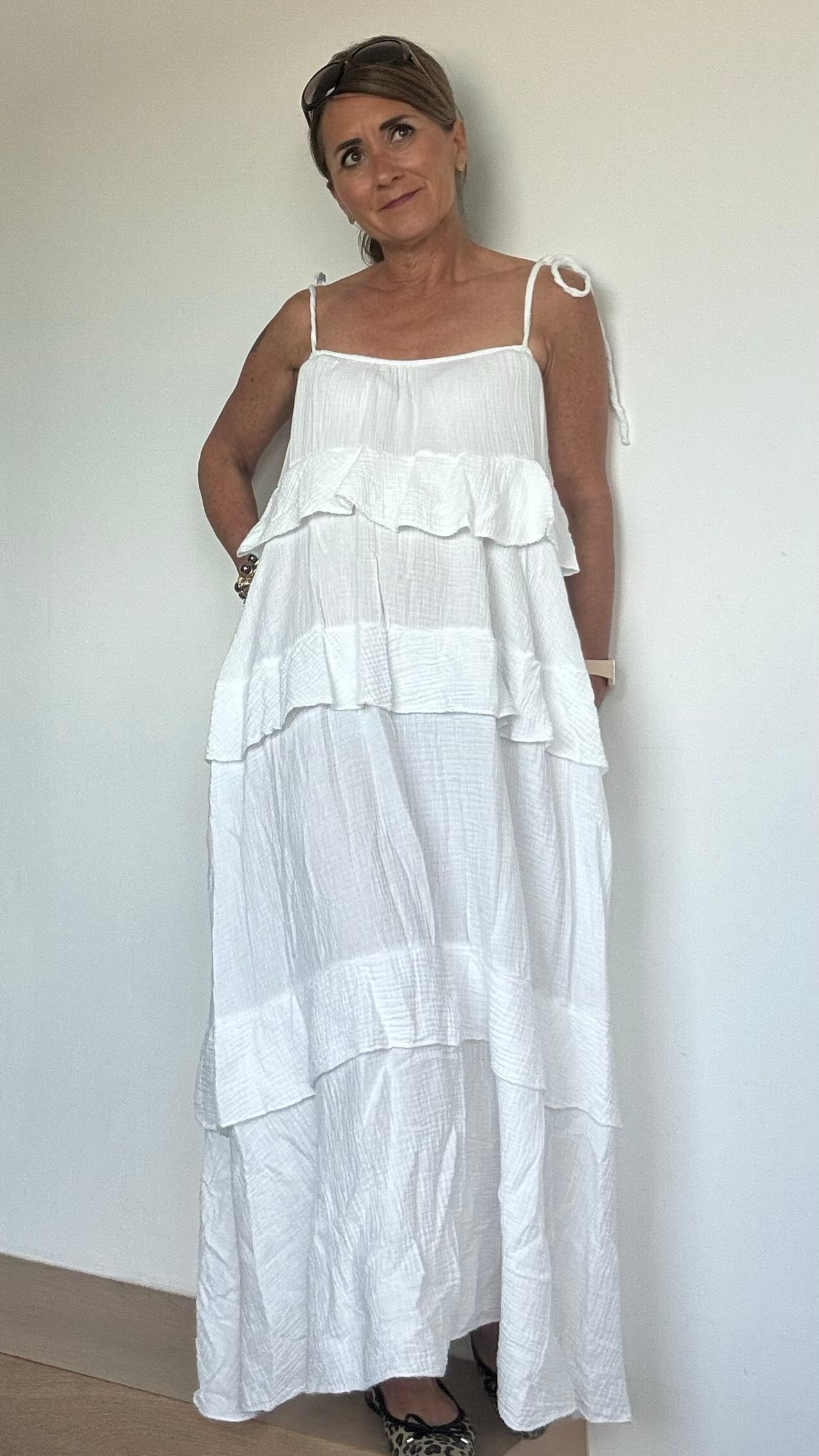 Luftiges Sommerkleid aus weichem Musselin in Weiß mit verstellbaren Spaghettiträgern und elastischem Ausschnitt. Das Kleid fällt locker und ist vorn etwas kürzer geschnitten als hinten. Drei Volantstufen sorgen für Bewegung und femininen Schwung. Perfekt kombinierbar mit Sandalen, Sneakers oder Ballerinas – ideal für warme Tage in der Stadt, am Strand oder auf der Sommerparty. Länge ca. 132 cm, passt locker von Größe 34–42, auch für Petite geeignet.