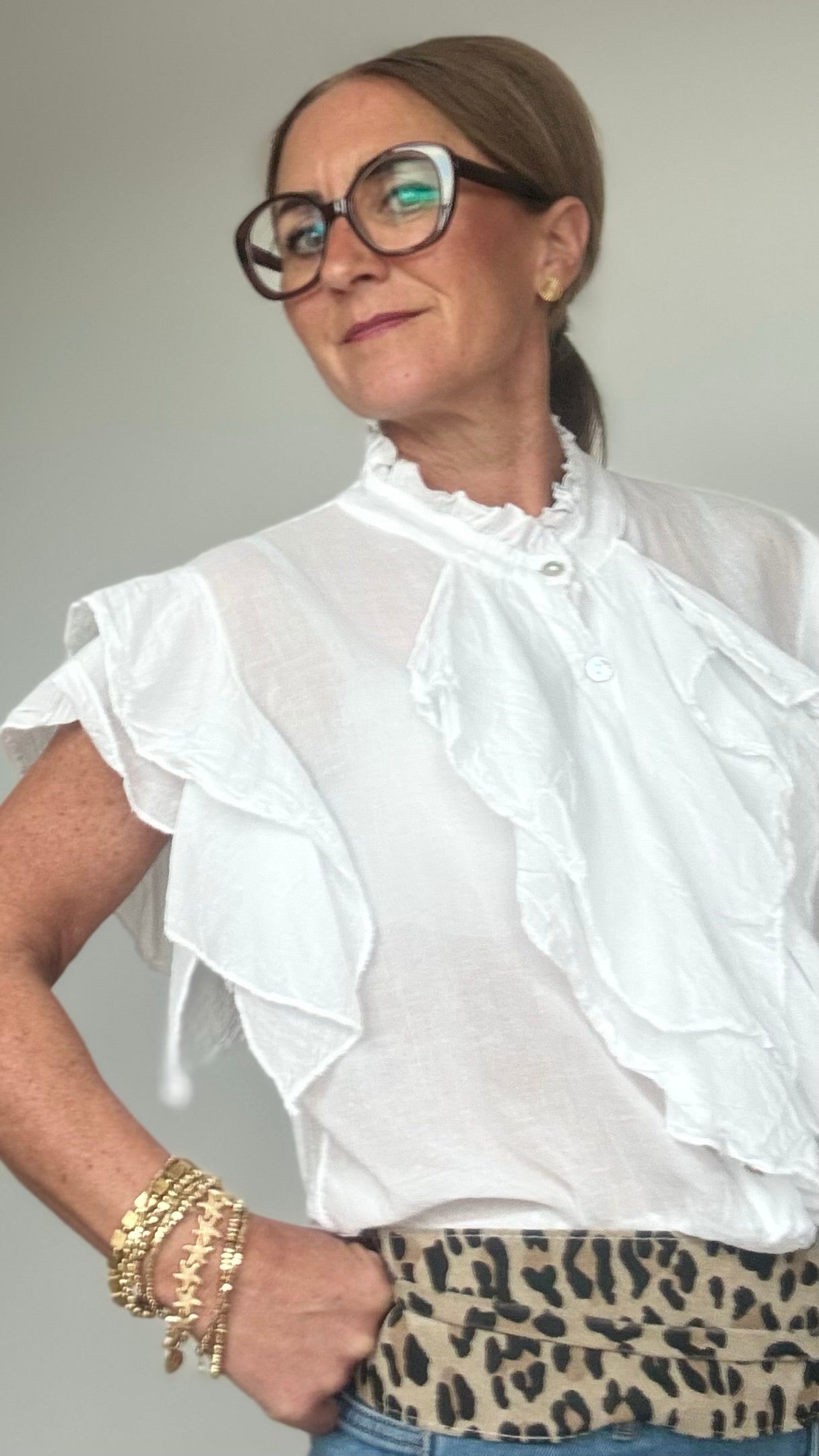 Ärmellose Bluse aus 100 % Baumwolle in zartem Offwhite mit feinen Details: Wasserfallartige Volants zieren die Knopfleiste sowie die leichten Volant-Ärmel. Die Bluse hat einen kleinen Stehkragen mit Rüschen, ist gerade geschnitten und etwa 62 cm lang. Locker und stilvoll kombiniert mit Jeans und Taillengürtel oder elegant mit Rock oder Blazer tragbar – ideal für feminine Looks mit Statement-Charakter.