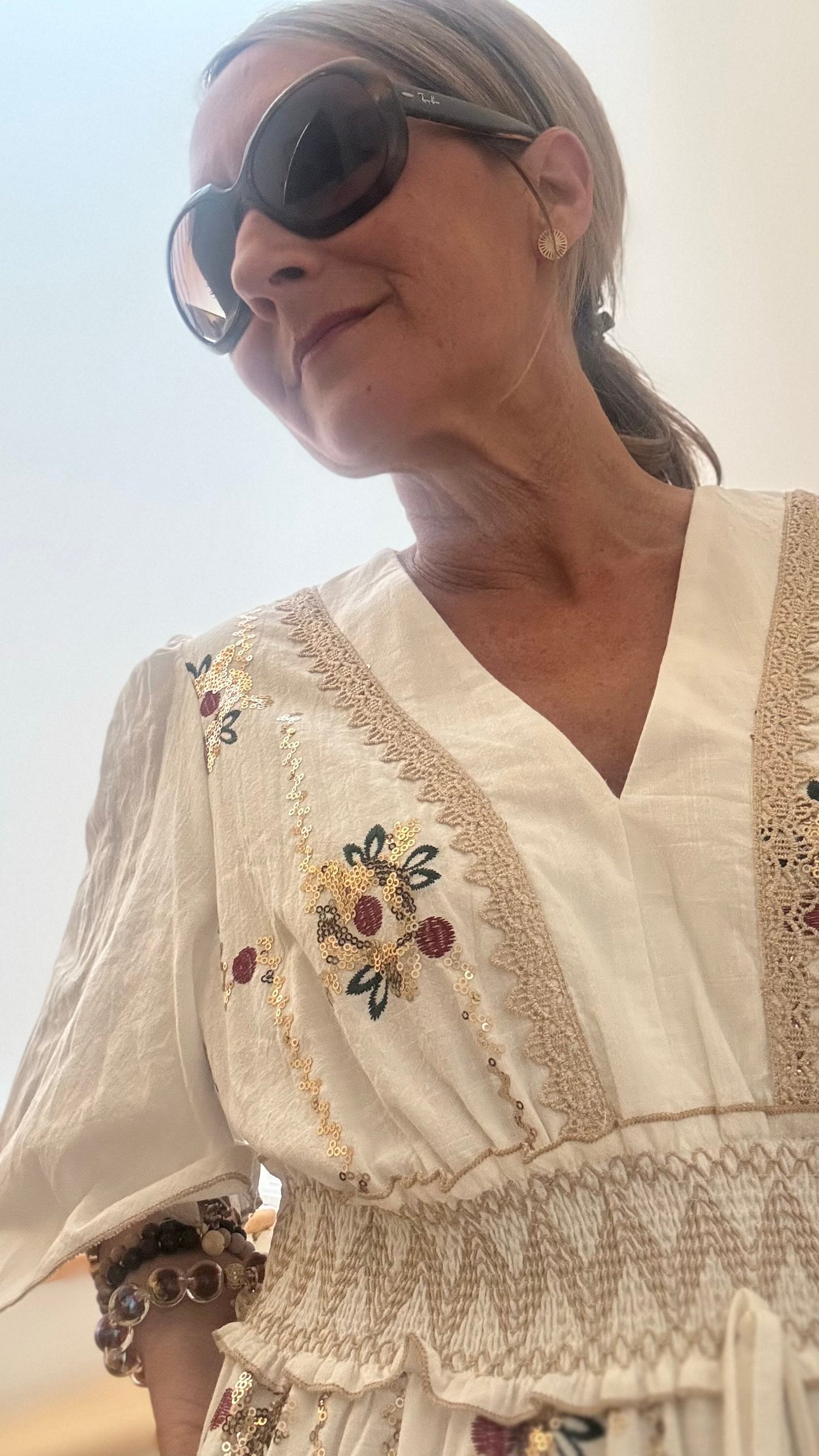 Maxikleid im Boho-Stil mit floraler Stickerei und Paillettendetails im Vorderteil. Kleid mit V-Ausschnitt, gesmoktem Bund und 3/4 Ärmeln, unterfüttert und locker fallend. Rückseite schlicht ohne Stickerei.