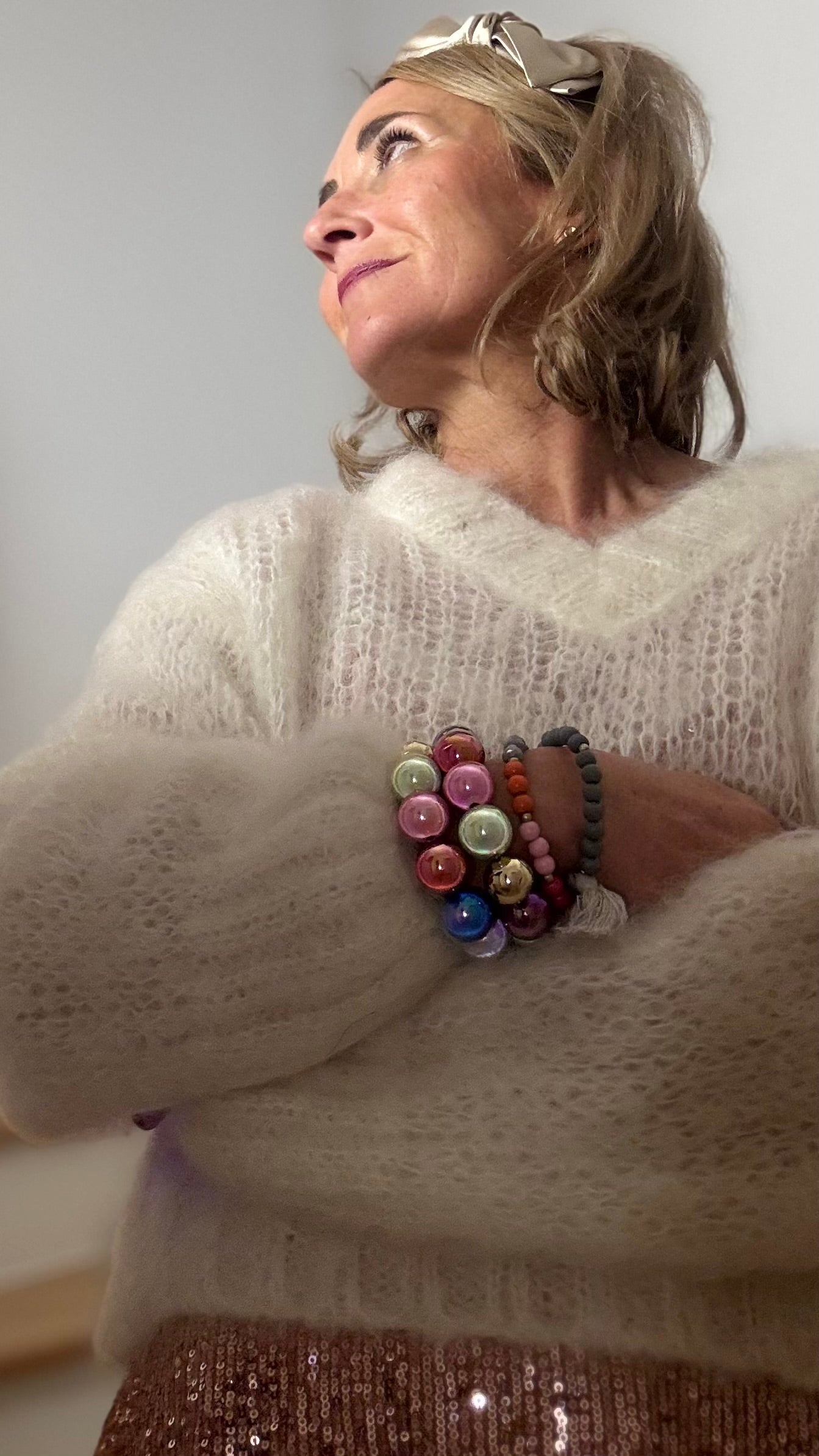 Elastisches Armband mit großen, glatt polierten Perlen in verschiedenen Farben wie Rosa, Hellblau, Grün und Apricot. Eine einzelne goldfarbene Akzentperle setzt einen ruhigen Kontrast. Getragen am Handgelenk zu einem hellen Strickpullover.