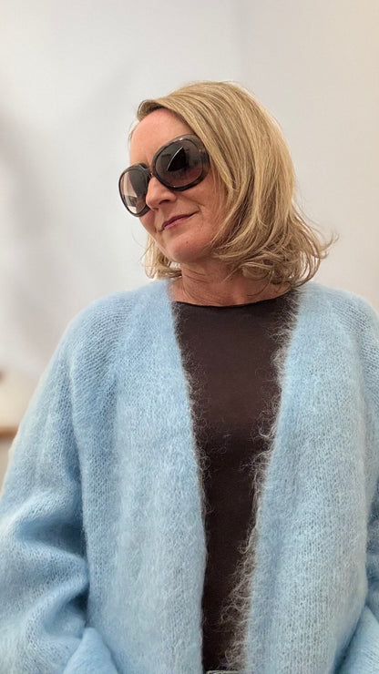Onesize Kid-Mohair Cardigan in Eisblau, locker und offen geschnitten, weich fallend mit fluffiger Struktur, kombiniert mit einem mochatonigen Oberteil.