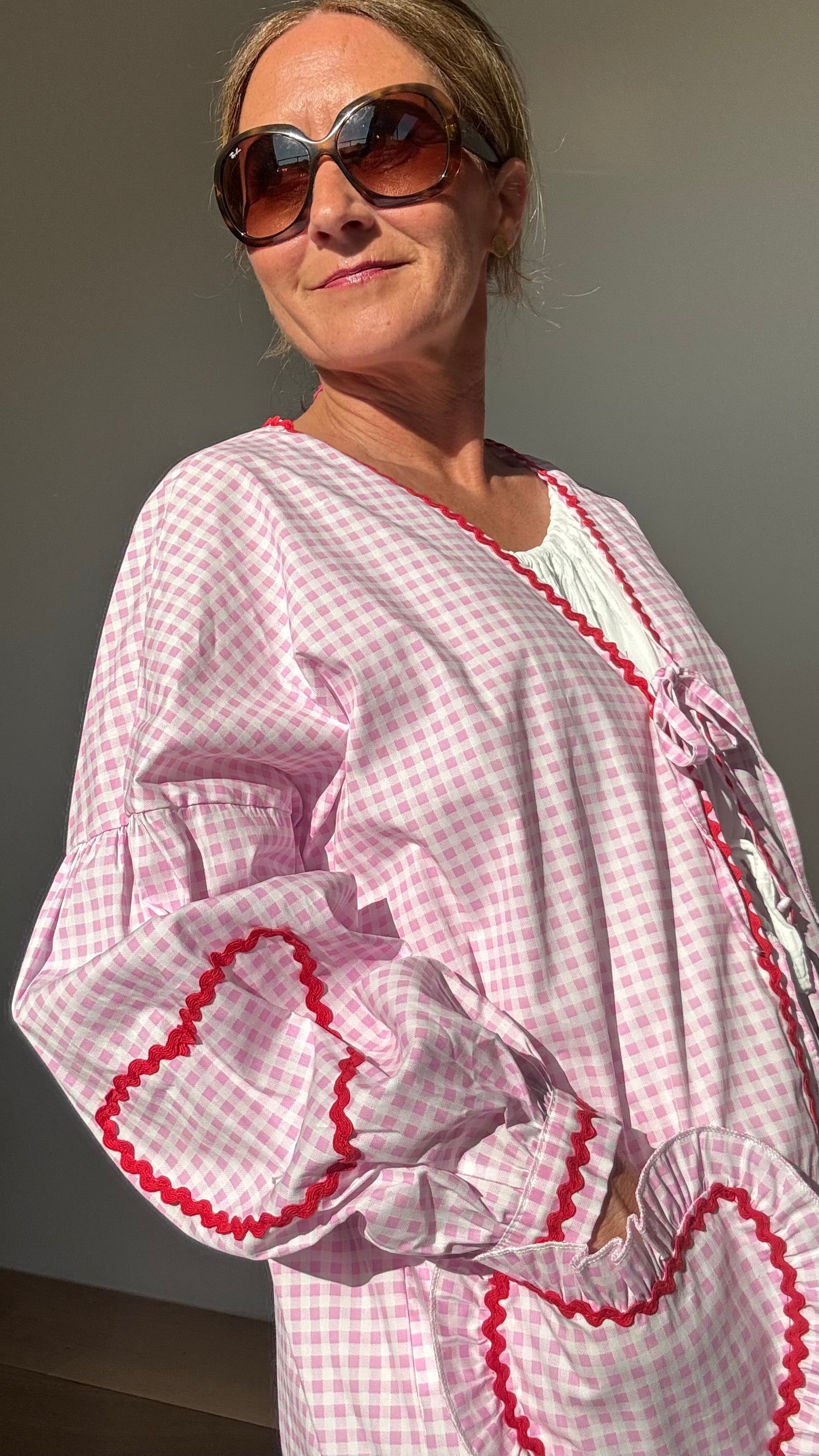 Rosa-weiß kariertes Baumwolljäckchen mit überschnittenen Schultern, Puffärmeln, roten Herzstickereien auf Ärmeln und herzförmigen Taschen. Schleifenverschluss vorn. Rückenlänge ca. 65 cm, passend für Größen 34–42