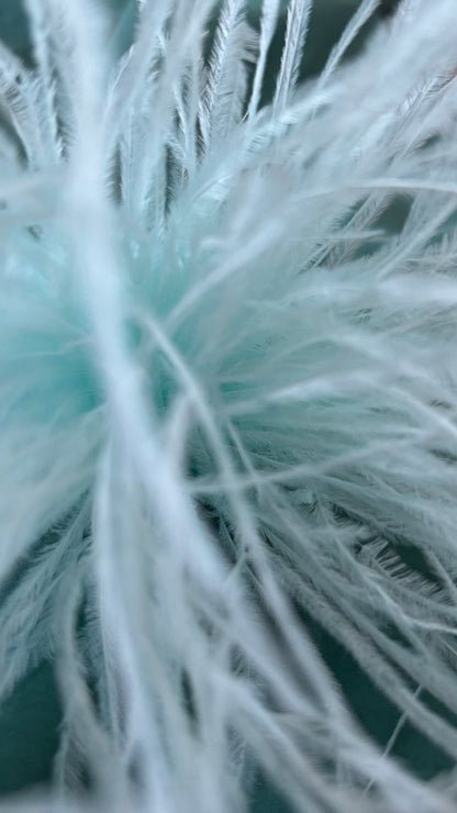 Zarte Brosche aus feinen Federn in Hellblau, flexibel tragbar als Anstecker oder Haarclip. Luftiges, extravagantes Accessoire für schlichte Outfits oder besondere Anlässe.