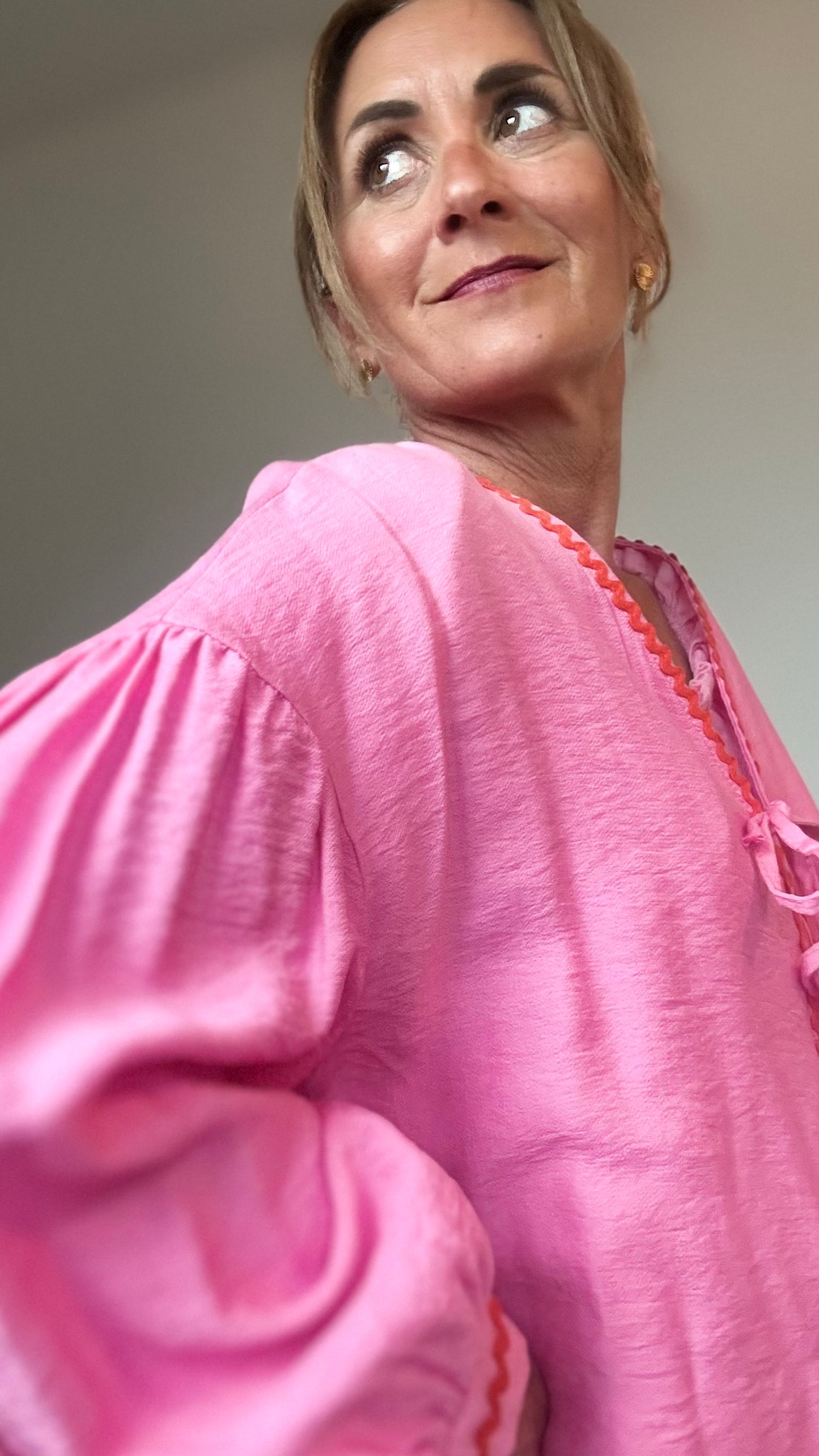 Blusen-Jäckchen aus pinkfarbener Viskose mit orangefarbener Zierkante, leichtem Puffärmel, überschnittenen Schultern und Bindebändern vorn. Rückenlänge 62 cm, locker geschnitten, vielseitig kombinierbar von Größe 34–40.