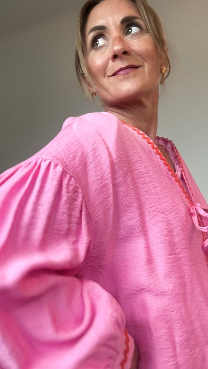 Blusen-Jäckchen aus pinkfarbener Viskose mit orangefarbener Zierkante, leichtem Puffärmel, überschnittenen Schultern und Bindebändern vorn. Rückenlänge 62 cm, locker geschnitten, vielseitig kombinierbar von Größe 34–40.