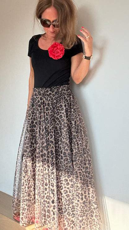 Frau trägt ein schwarzes T-shirt mit einer roten Bluembrosche, dazu den Tüllrock in der Farbvariante heller Leo-Print. Details findest du in unserer Produktbeschreibung.