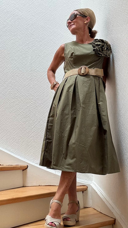 Olivfarbenes Baumwollkleid mit elastischem Taillenbereich und großer Kamelien-Brosche – Camellia Charm Dress von Miss Lotti.

