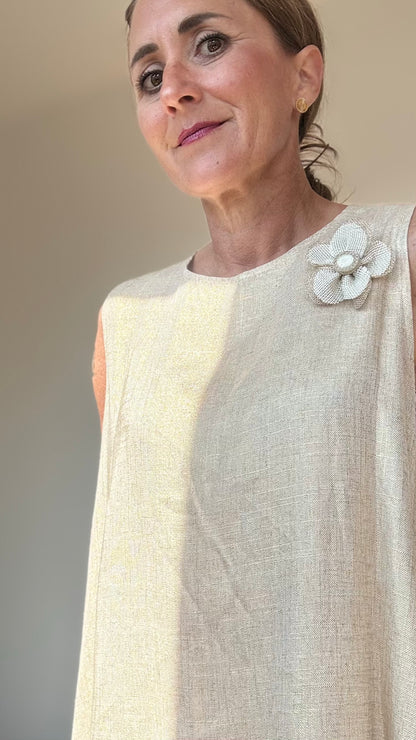 Ärmelloses Sommerkleid „Golden Glow“ in edlem Goldton. A-Linien-Schnitt mit 93 cm Länge, tiefen Armausschnitten und Rundhalsausschnitt mit Knopfverschluss hinten. Hergestellt aus leichtem Rayon-Leinen-Mix. Verziert mit abnehmbarer, goldener Blumenbrosche. Passend für Größen 34–38. Ideal für elegante Sommeranlässe.