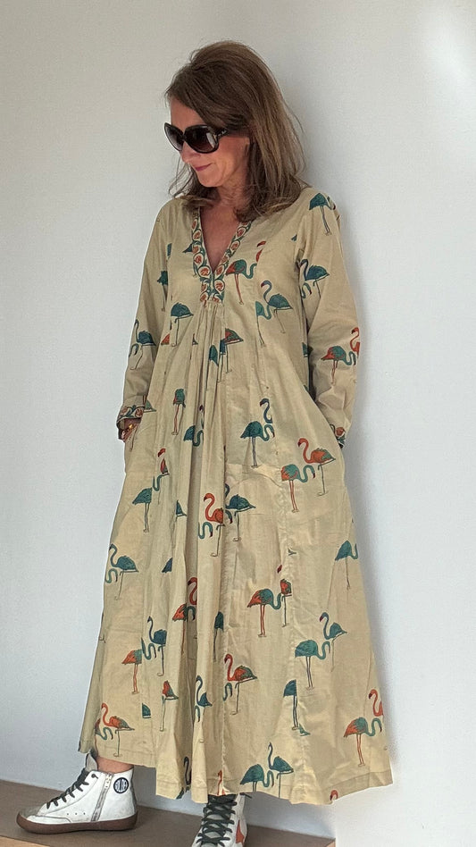 Kleid Melbourne im Tunika-Stil aus 100% Baumwolle mit V-Ausschnitt. Gesamtlänge 124 cm, Brustweite 84-86 cm, Taille 74-80 cm, Hüfte 94-98 cm. Beige mit petrol- und orangefarbenen Flamingos. Eingriffstaschen, atmungsaktiver Stoff. Ideal für Sommer, bringt Farbe in deinen Alltag