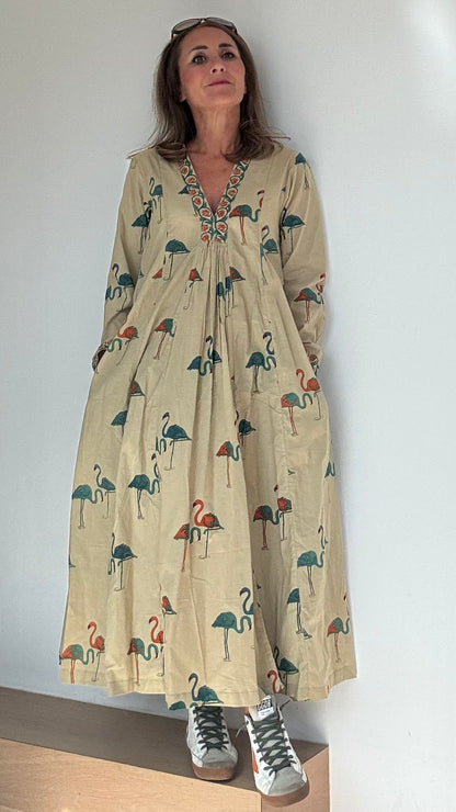 Kleid Melbourne im Tunika-Stil aus 100% Baumwolle mit V-Ausschnitt. Gesamtlänge 124 cm, Brustweite 84-86 cm, Taille 74-80 cm, Hüfte 94-98 cm. Beige mit petrol- und orangefarbenen Flamingos. Eingriffstaschen, atmungsaktiver Stoff. Ideal für Sommer, bringt Farbe in deinen Alltag