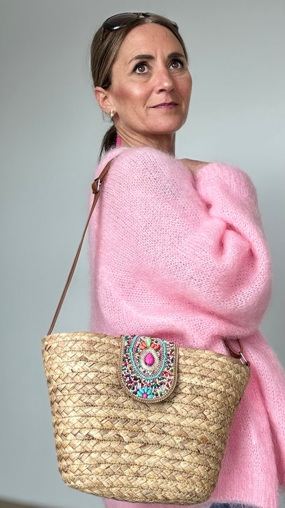 Boho-Umhängetasche aus geflochtenem Korb mit verstellbarem Schulterriemen. Die Schnalle ist kunstvoll mit Perlen- und Steinbesatz verziert. Die Tasche ist mit beigem Stoff gefüttert, hat ein kleines Innenfach und lässt sich mit einem Reißverschluss sicher schließen. Kompakte Größe mit genügend Platz für die wichtigsten Essentials – perfekt für den Alltag oder besondere Anlässe.