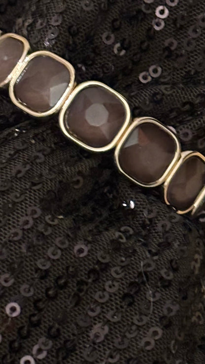 Kristallarmband mit 13 taupefarbenen, facettierten 15-mm-Steinen in goldfarbener Fassung. Schlankes, elastisches Design mit warmem Kristallglanz.