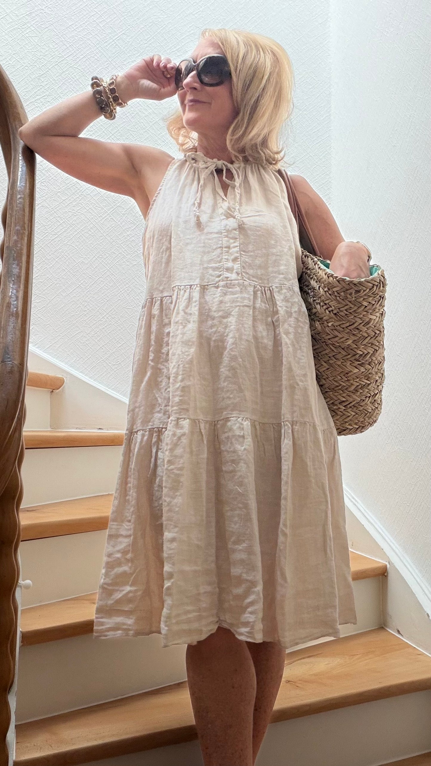 Midi-Leinenkleid aus 100 % Leinen mit femininem A-Linien-Schnitt und stufenweise gearbeitetem Rock. Der elastische V-Ausschnitt kann offen oder mit Bindeband getragen werden. Luftiger Naturstoff, Länge ca. 94 cm, Achselweite ca. 54 cm. Onesize passend für Größe 34–40. Vielseitig kombinierbar für Alltag, Büro und besondere Anlässe.