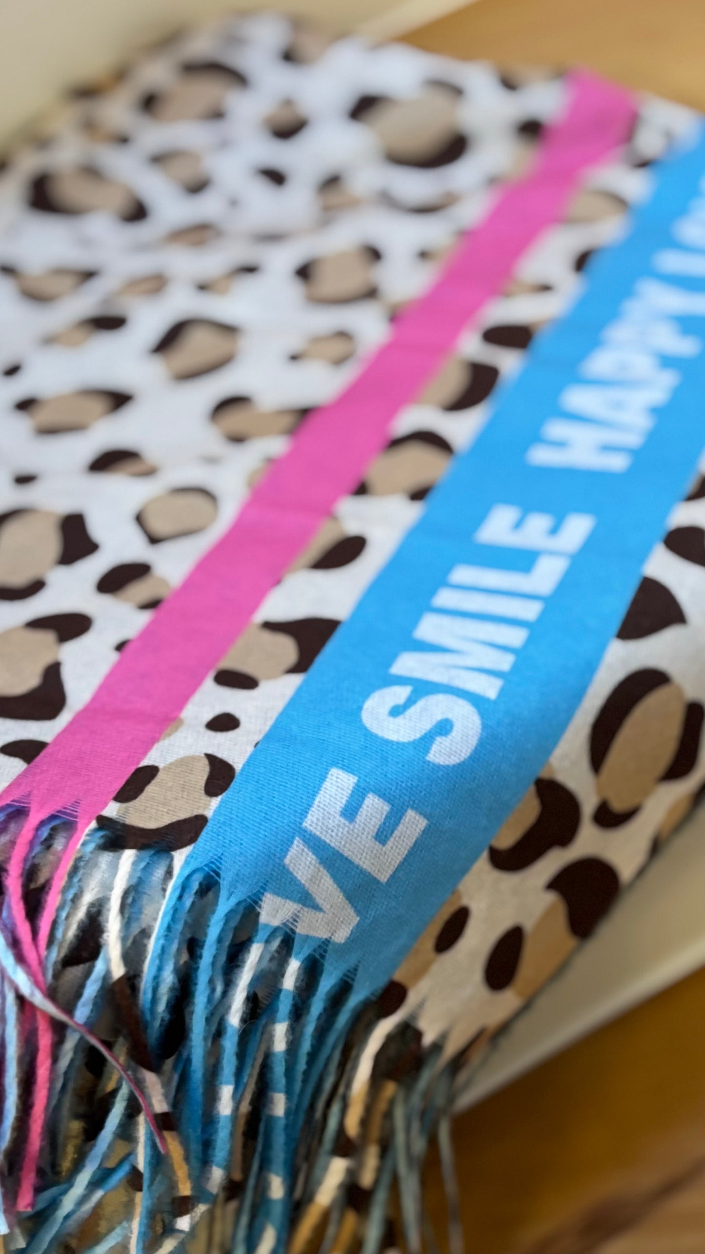Frühlingshafter Leo-Schal in kräftigem Hellblau mit beidseitigem Druck und Schriftzug ‚HAPPY I SMILE I LOVE‘, aus weicher Viskose mit Fransen