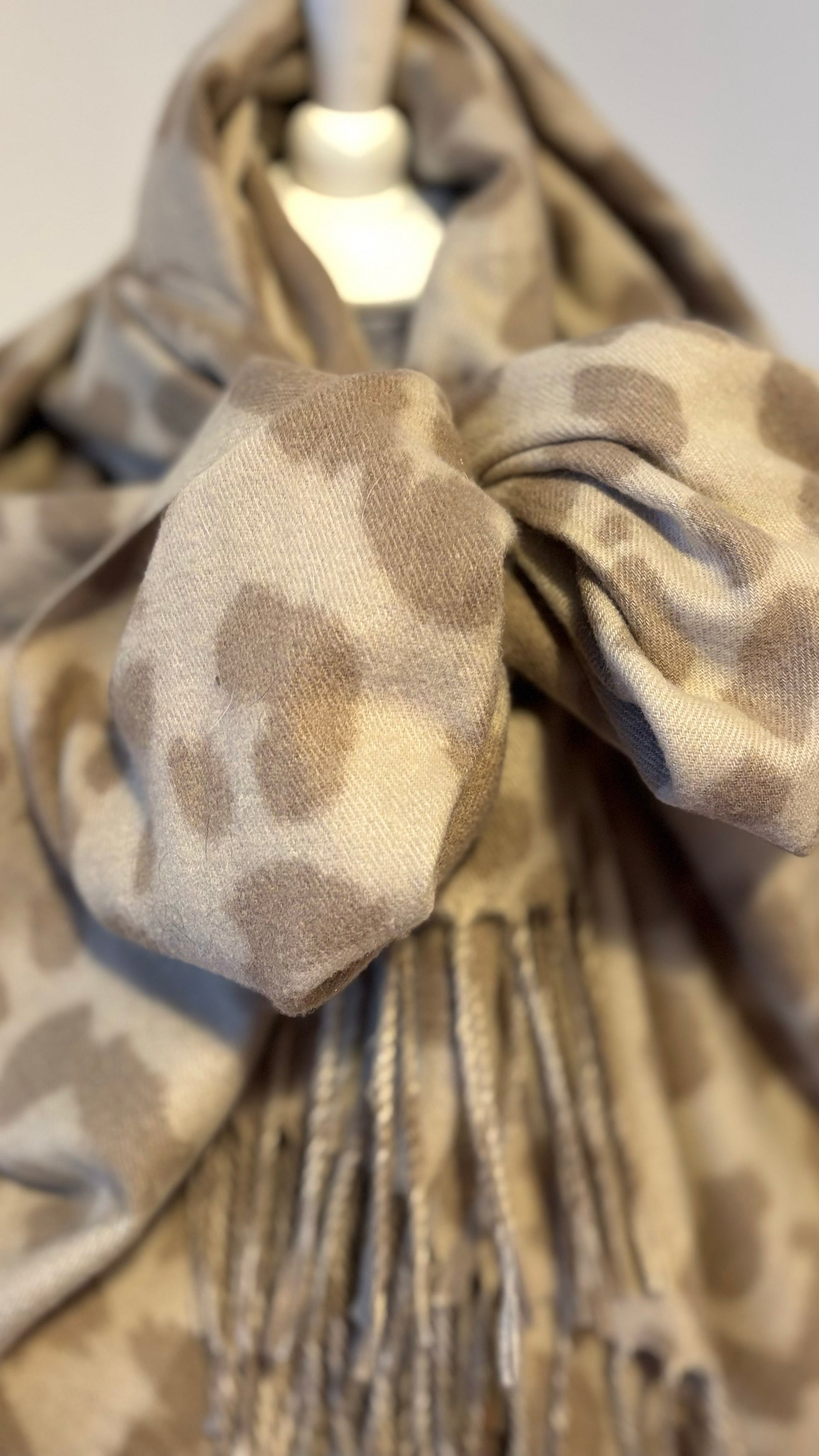 Leo Signature Schal mit klassischem Leopardenmuster, locker um den Hals getragen. Weicher Viskoseschal mit Fransen, kombiniert zu einem schwarzen Outfit.