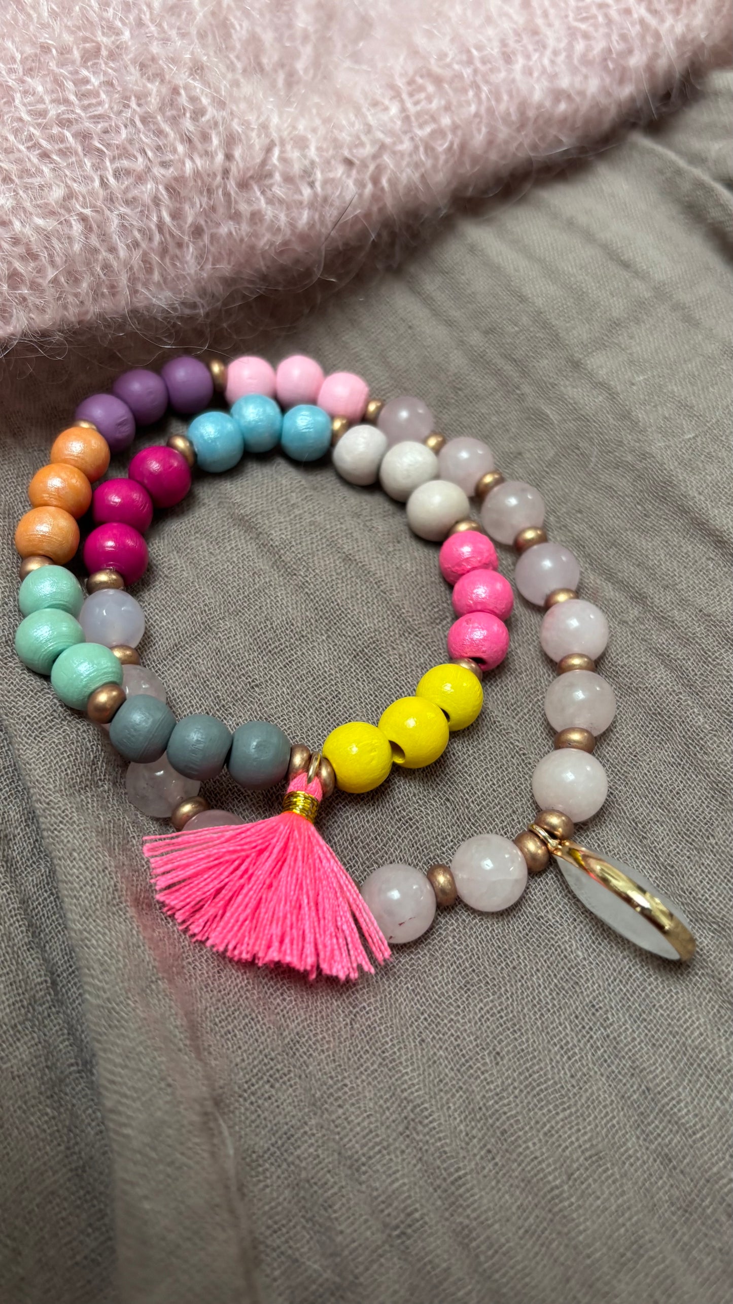 Handgefertigtes Mala-Armband aus Rosenquarz- und Regenbogen-Holzperlen mit goldfarbenen Details, pinker Quaste und Rosenquarz-Anhänger.