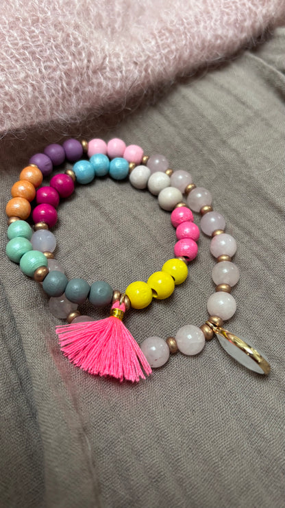 Handgefertigtes Mala-Armband aus Rosenquarz- und Regenbogen-Holzperlen mit goldfarbenen Details, pinker Quaste und Rosenquarz-Anhänger.