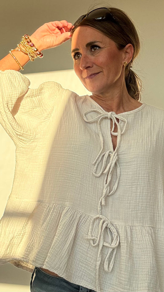 Luftige Bluse 'Pure Breeze' aus weichem Musselin in Beige. Mit Schößchen-Saum, 3/4-Ballonärmeln mit Gummibund und dekorativer Schleifenfront. Femininer Schnitt mit lockerer Passform (Größe 34-40). Rückenlänge: 57 cm. Perfekt für lässige oder romantische Looks – kombinierbar mit Jeans oder Cardigan