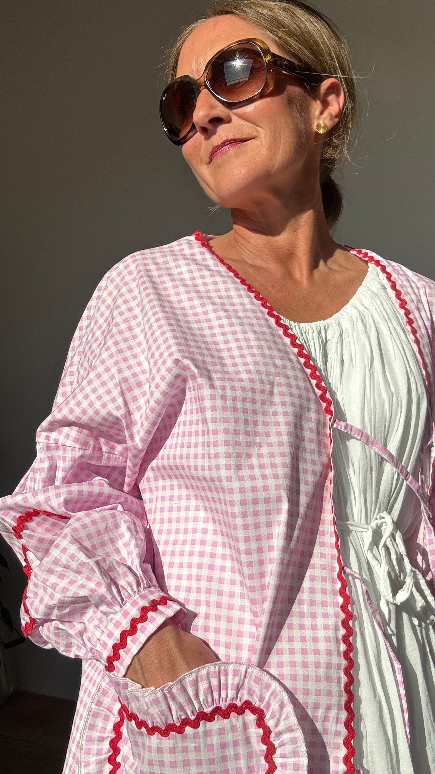 Rosa-weiß kariertes Baumwolljäckchen mit überschnittenen Schultern, Puffärmeln, roten Herzstickereien auf Ärmeln und herzförmigen Taschen. Schleifenverschluss vorn. Rückenlänge ca. 65 cm, passend für Größen 34–42