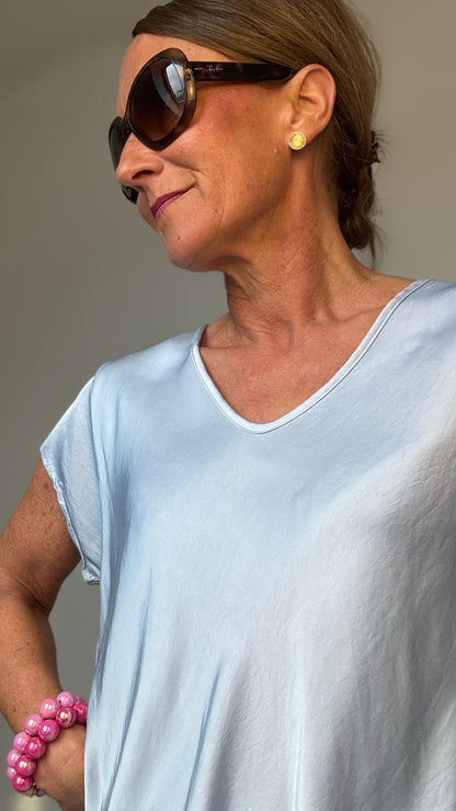 Fließendes Oberteil aus 100% Viskose mit dezentem Glanz. Die Satin Glow Blouse hat kurze Ärmel, einen sanften V-Ausschnitt vorne und hinten und eine luftige Passform. Mit einer Länge von ca. 62 cm und einer Breite von ca. 50 cm passt sie schmalen Kleidergrößen 34–40. Perfekt kombinierbar mit Jeans, Röcken, Cardigans und Blazern für einen stilvollen Look.