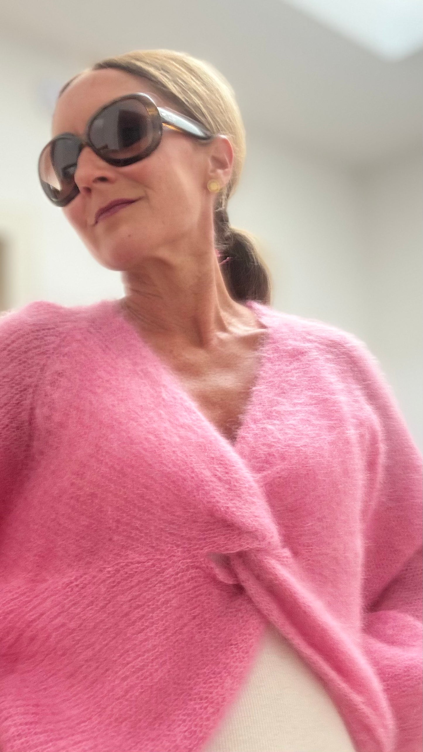 Leichter Kid-Mohair-Pullover Twist & Cozy in verschlungenem Design, vorne kürzer geschnitten, in Bubblegum Pink, getragen über einem Sommerkleid.