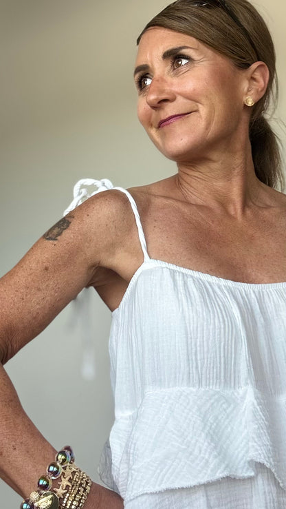 Luftiges Sommerkleid aus weichem Musselin in Weiß mit verstellbaren Spaghettiträgern und elastischem Ausschnitt. Das Kleid fällt locker und ist vorn etwas kürzer geschnitten als hinten. Drei Volantstufen sorgen für Bewegung und femininen Schwung. Perfekt kombinierbar mit Sandalen, Sneakers oder Ballerinas – ideal für warme Tage in der Stadt, am Strand oder auf der Sommerparty. Länge ca. 132 cm, passt locker von Größe 34–42, auch für Petite geeignet.