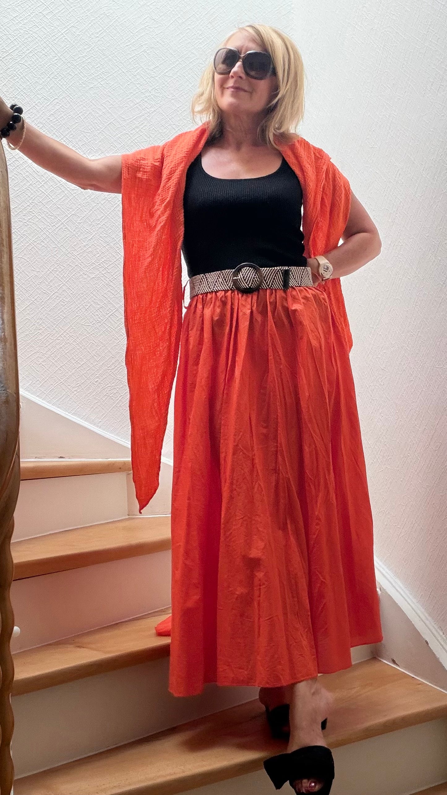Maxirock "Sunset Cotton" in warmem Orange aus 100 % Baumwolle. Luftig fallender, weitschwingender Rock mit elastischem Bund und dekorativem Bindegürtel. Vielseitig kombinierbar mit Tops, Blusen oder leichtem Strick für sommerliche und elegante Alltagslooks. Onesize passend für Größe 34–40.