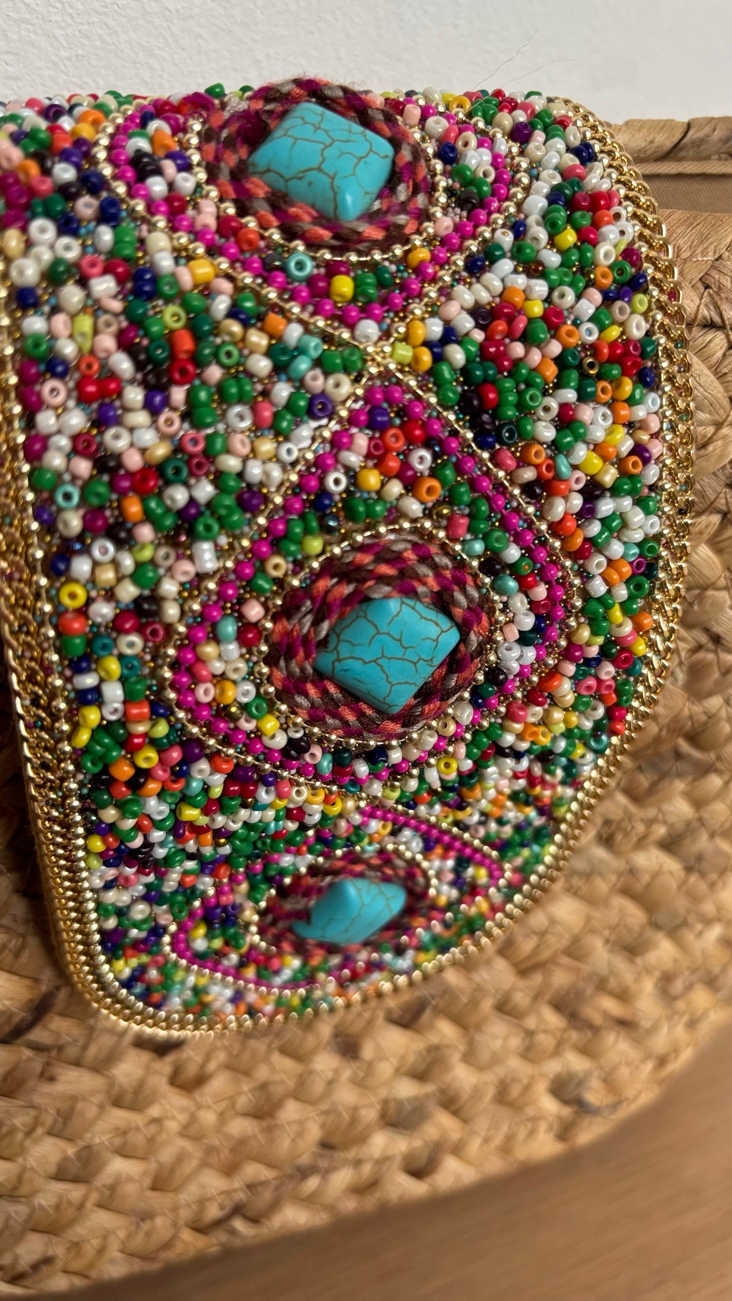 Boho-Umhängetasche aus geflochtenem Korb mit verstellbarem Schulterriemen. Die Schnalle ist kunstvoll mit Perlen- und Steinbesatz verziert. Die Tasche ist mit beigem Stoff gefüttert, hat ein kleines Innenfach und lässt sich mit einem Reißverschluss sicher schließen. Kompakte Größe mit genügend Platz für die wichtigsten Essentials – perfekt für den Alltag oder besondere Anlässe.