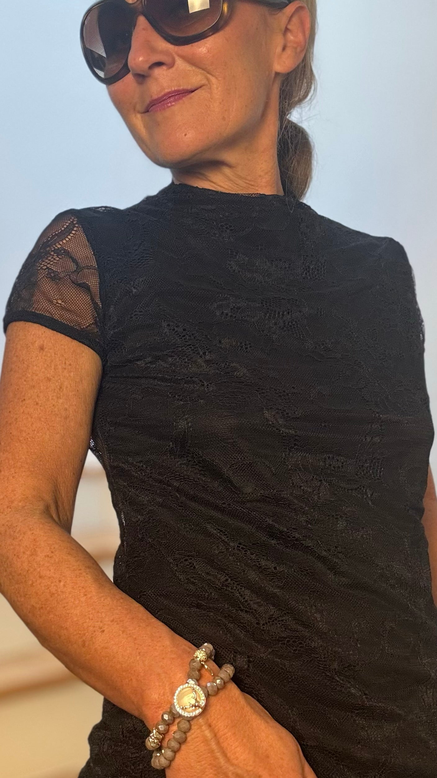 Mystic Lace Shirt aus elastischer Spitze mit kurzen Ärmeln und kleinem Stehkragen. Beidseitig tragbar: unterlegte Vorderseite oder Spitze vorne, Länge 63 cm.“