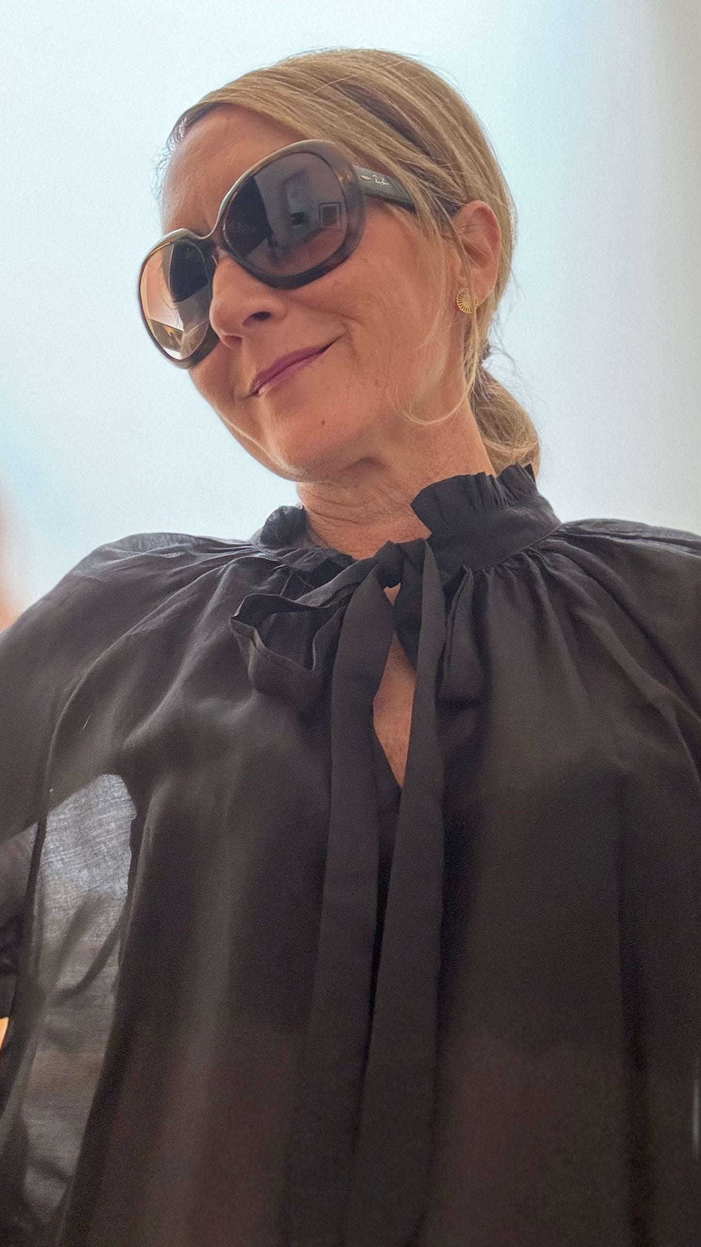 Schwarze, leicht transparente Bluse mit Rüschenkragen und Schleife am Ausschnitt. Luftiger, fließender Stoff mit langen Ärmeln und Gummibund. Locker geschnittene Bluse, kombiniert mit Jeans. Länge ca. 66 cm, passend für Größen 34–42.