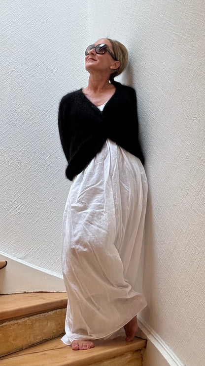 Leichter Kid-Mohair-Pullover Twist & Cozy in verschlungenem Design, vorne kürzer geschnitten, in Schwarz, getragen über einem Sommerkleid.