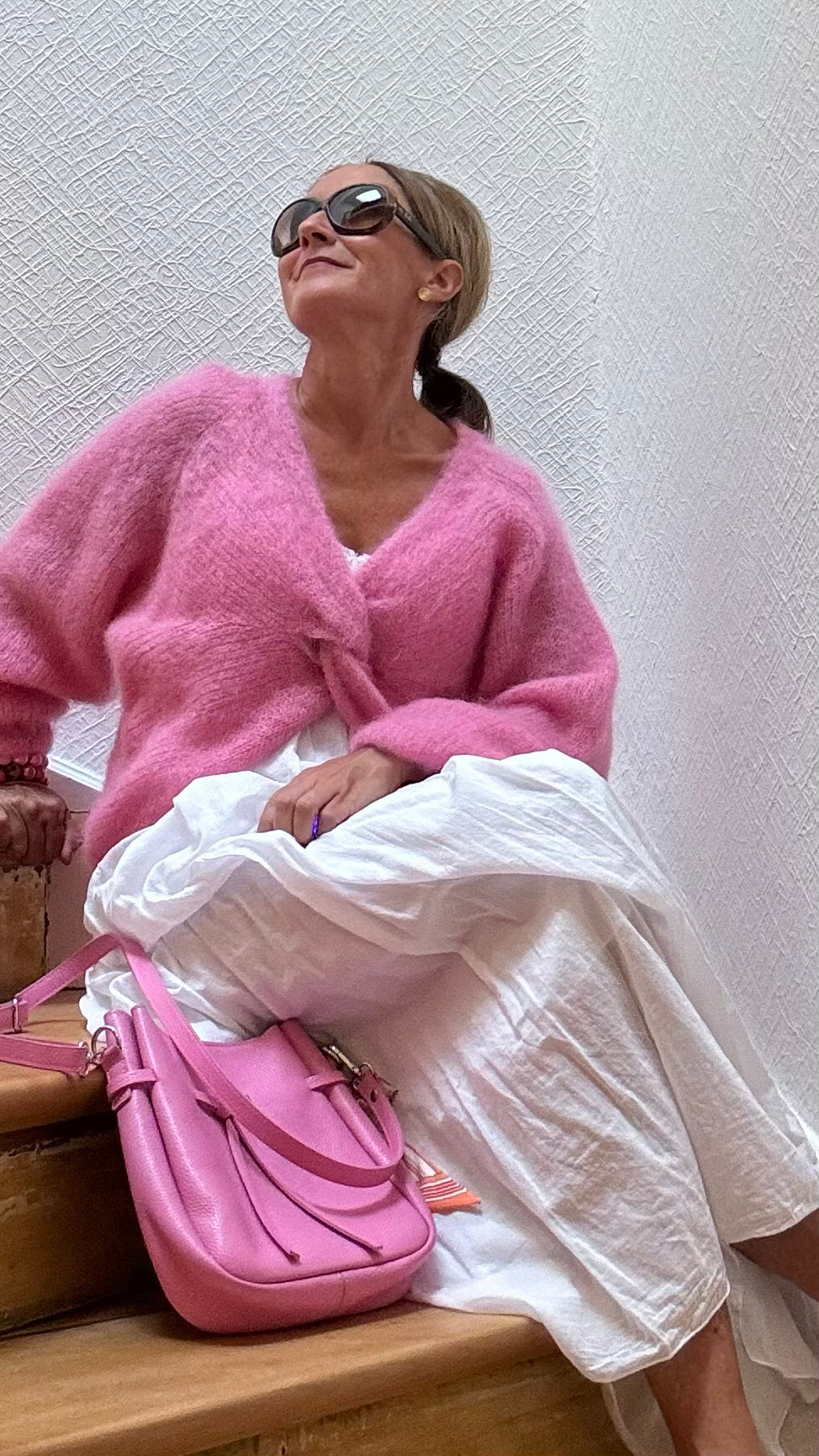 Leichter Kid-Mohair-Pullover Twist & Cozy in verschlungenem Design, vorne kürzer geschnitten, in Cremefarbe, getragen über einem Sommerkleid.