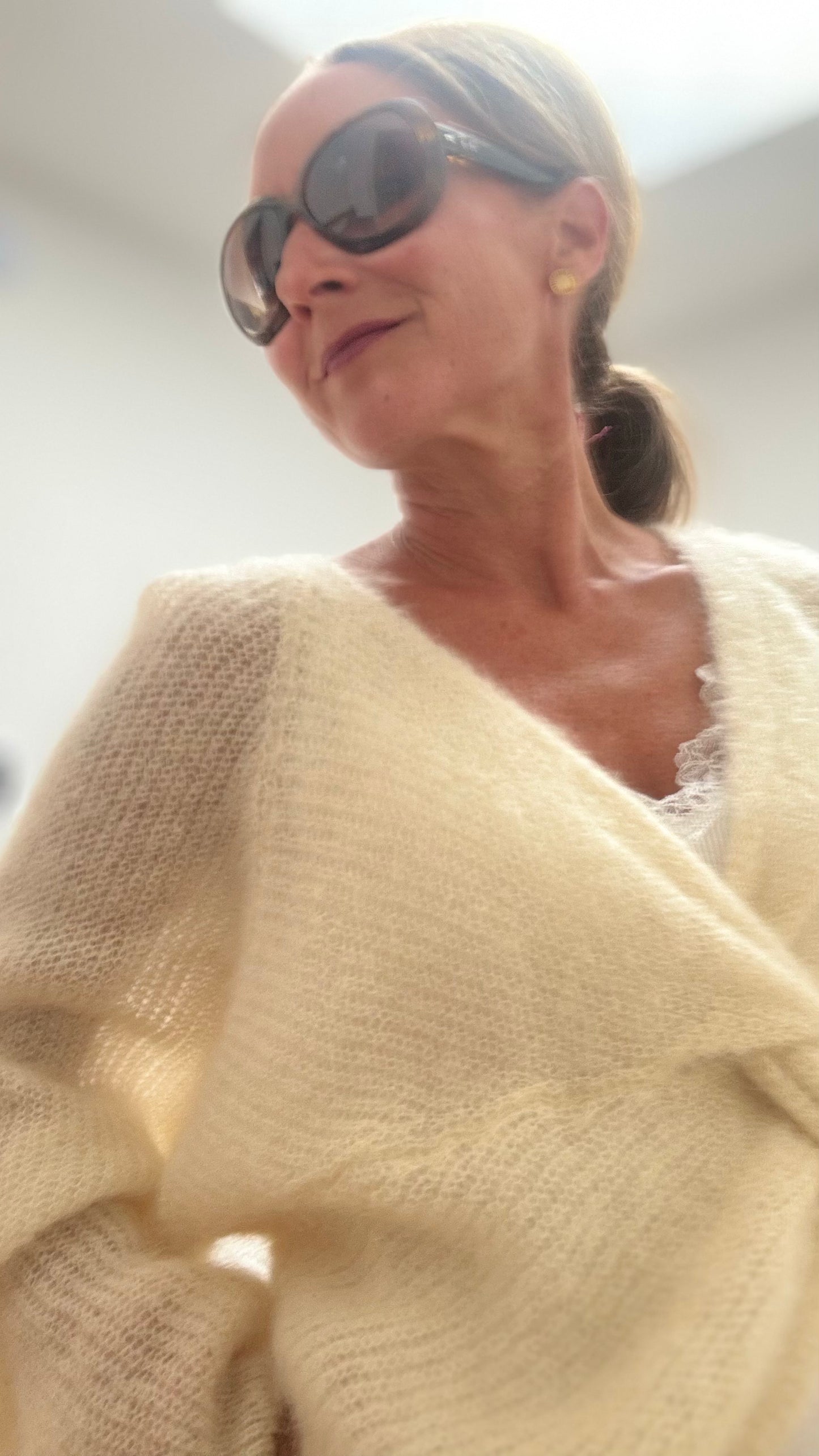 Leichter Kid-Mohair-Pullover Twist & Cozy in verschlungenem Design, vorne kürzer geschnitten, in Butter Lemon, getragen über einem Sommerkleid.