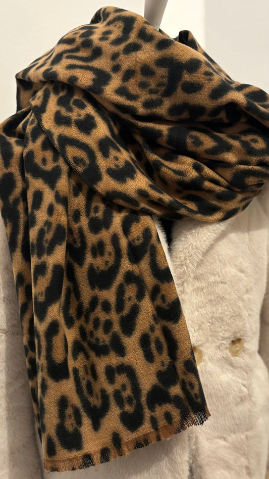 Weicher Schal mit klassischem Leo-Print in warmen Naturtönen. Großformat mit feinen Fransen, locker über einen schwarzen Mantel gelegt. Wirkt edel, cozy und modisch zugleich.
