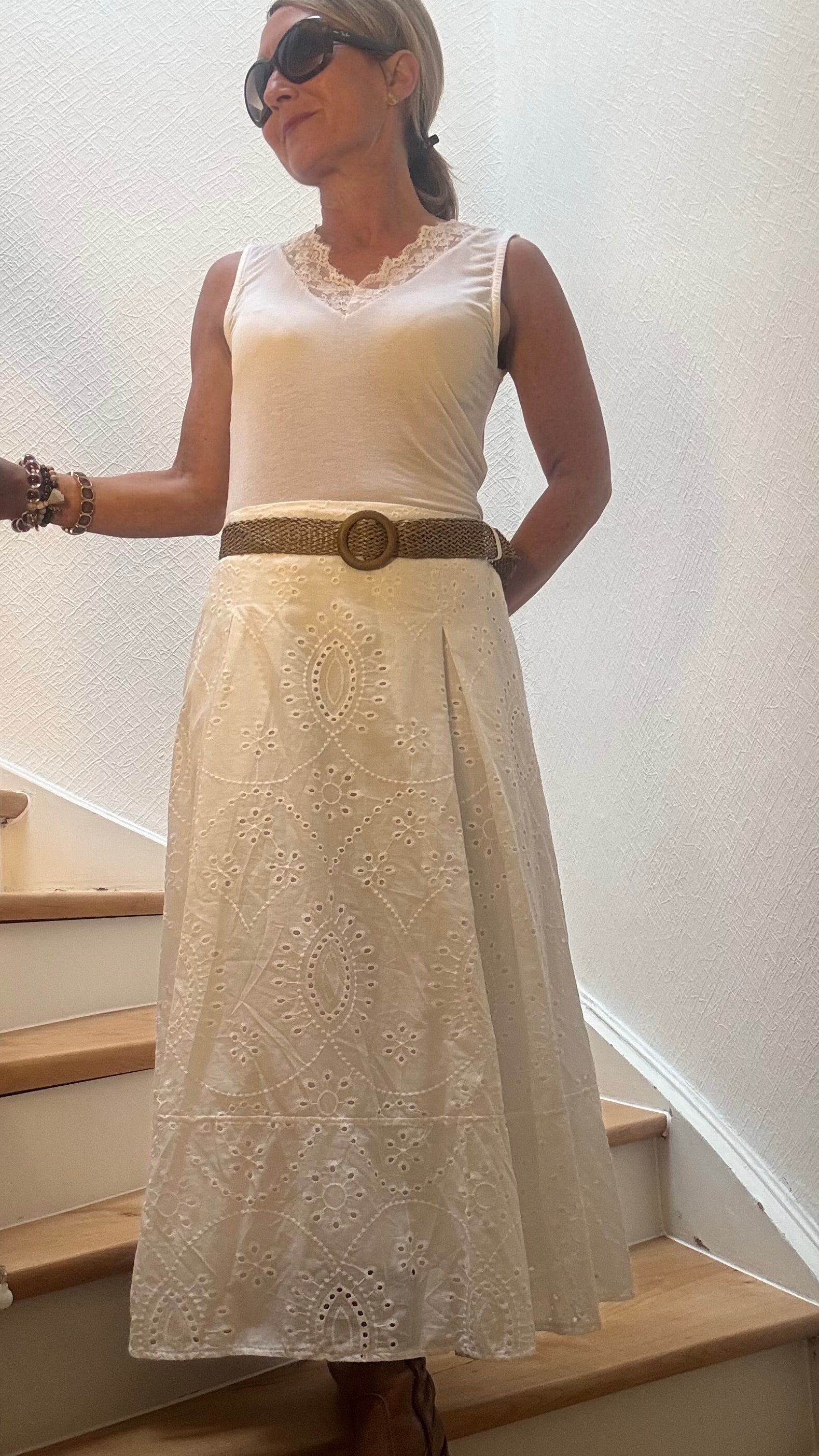 Weißer,langer Baumwollrock mit Broderie Anglaise und A-Linie. Vorne glatter Bund mit Ziergürtel, hinten elastisch. Unterfüttert und mit Kellerfalten im Vorderteil. Femininer Sommerrock, kombiniert mit hellem Top.