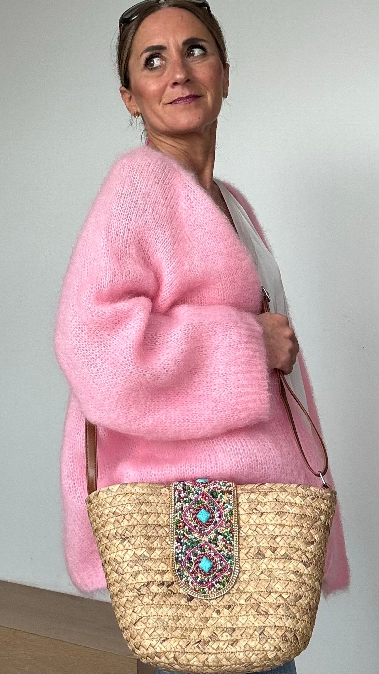 Boho-Umhängetasche aus geflochtenem Korb mit verstellbarem Schulterriemen. Die Schnalle ist kunstvoll mit Perlen- und Steinbesatz verziert. Die Tasche ist mit beigem Stoff gefüttert, hat ein kleines Innenfach und lässt sich mit einem Reißverschluss sicher schließen. Kompakte Größe mit genügend Platz für die wichtigsten Essentials – perfekt für den Alltag oder besondere Anlässe.